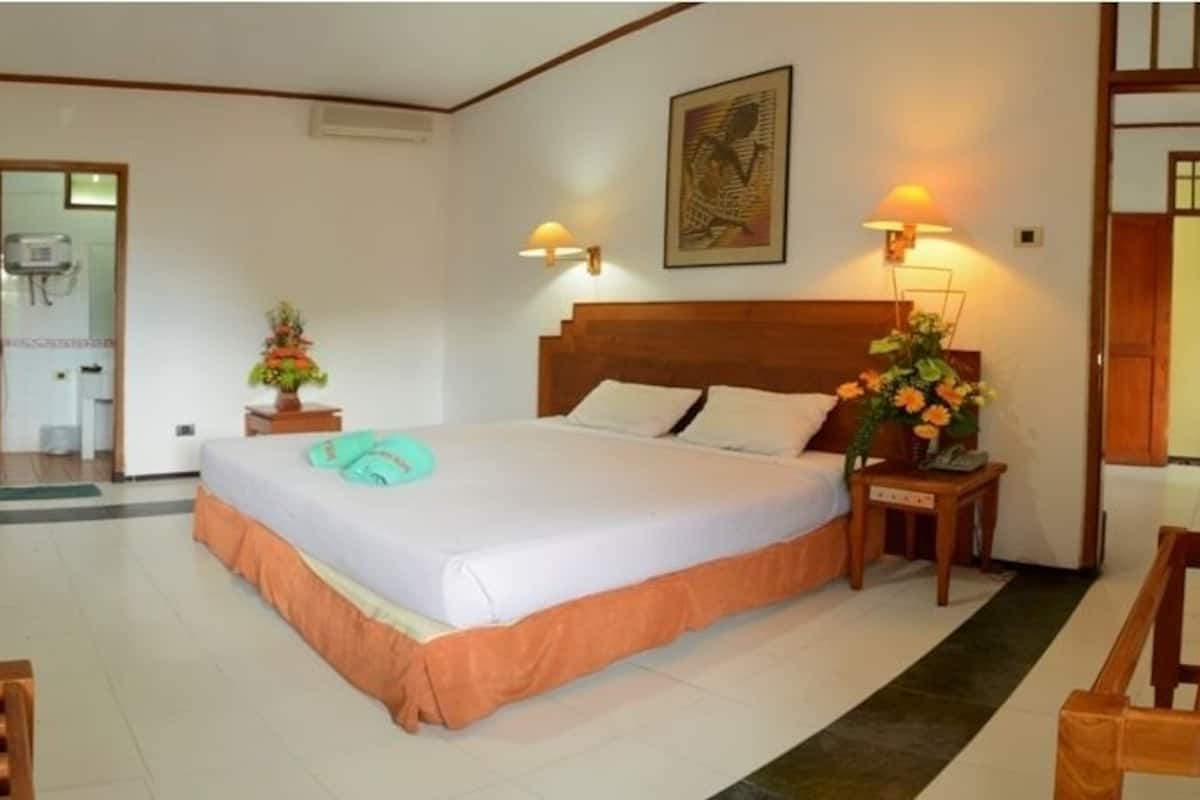 Una habitación de hotel con una cama, mesitas de noche, un escritorio y una silla.