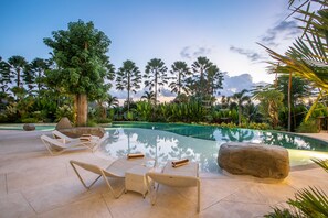 A poolside area with lounge chairs and a large rock.