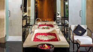 A hotel lobby with a long reception desk, two sinks with rose petals, a chair with a cushion, and a small bowl with flowers. - Sanctoo Suites and Villas (Sukawati)
