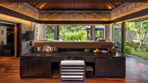 A modern kitchen with a central island, a built-in oven, and a large window offering a view of greenery. - Sanctoo Suites and Villas (Sukawati)