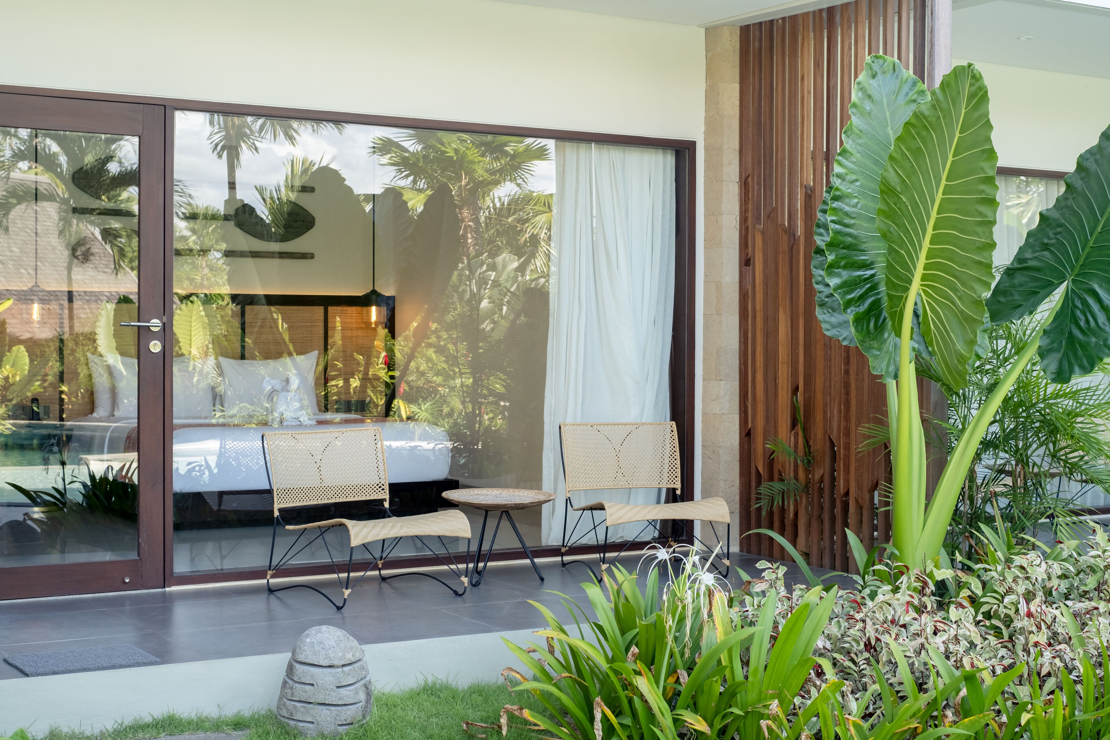 Un área de estar moderna al aire libre con una puerta de cristal que da a un dormitorio.