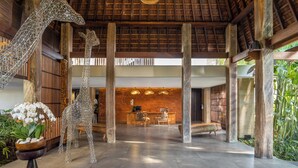 A spacious lobby with a high ceiling, wooden beams, and a reception desk. - Sanctoo Suites and Villas (Sukawati)