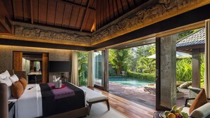 A spacious bedroom with a large bed, a TV, and a view of a swimming pool. - Sanctoo Suites and Villas (Sukawati)