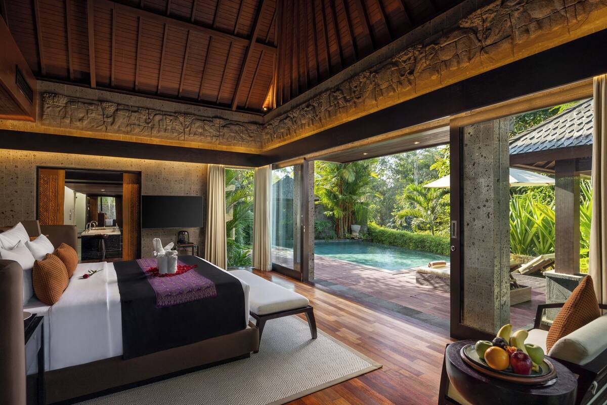 Um quarto espaçoso com uma cama grande, televisão e vista para uma piscina.