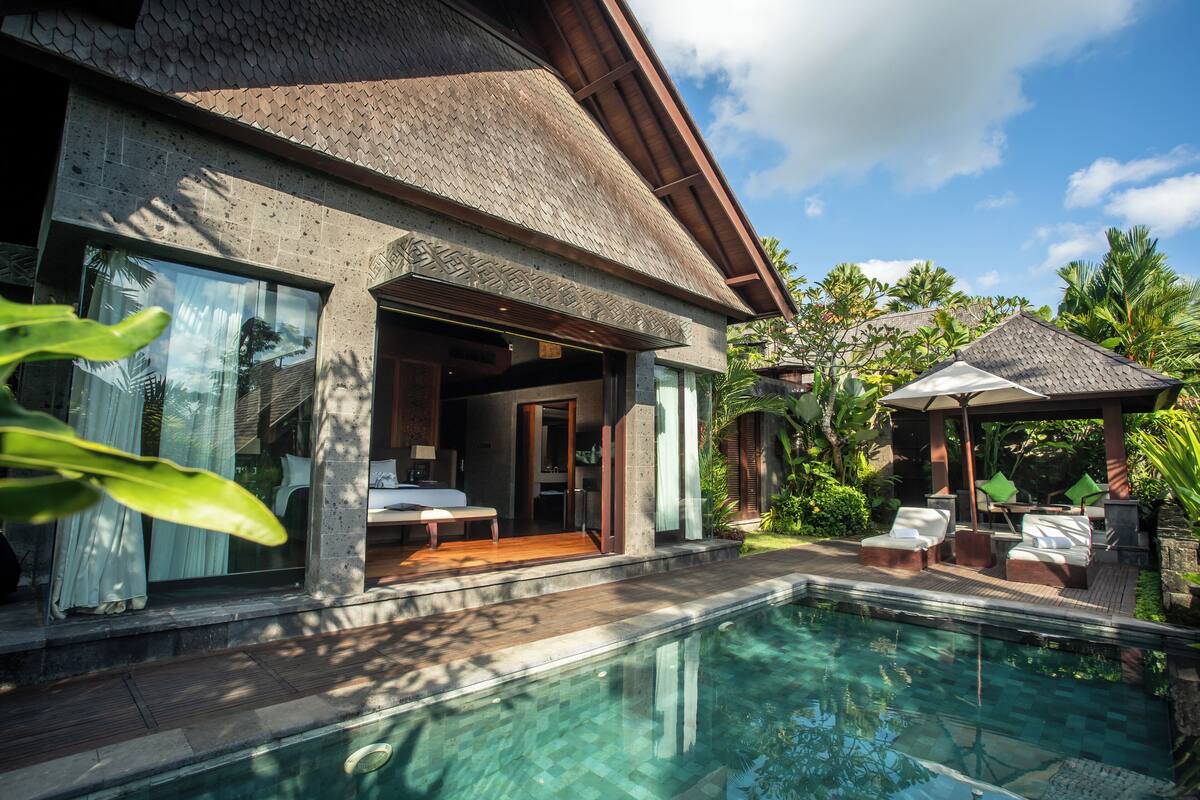 Um resort moderno com piscina, área de estar externa e vegetação exuberante.
