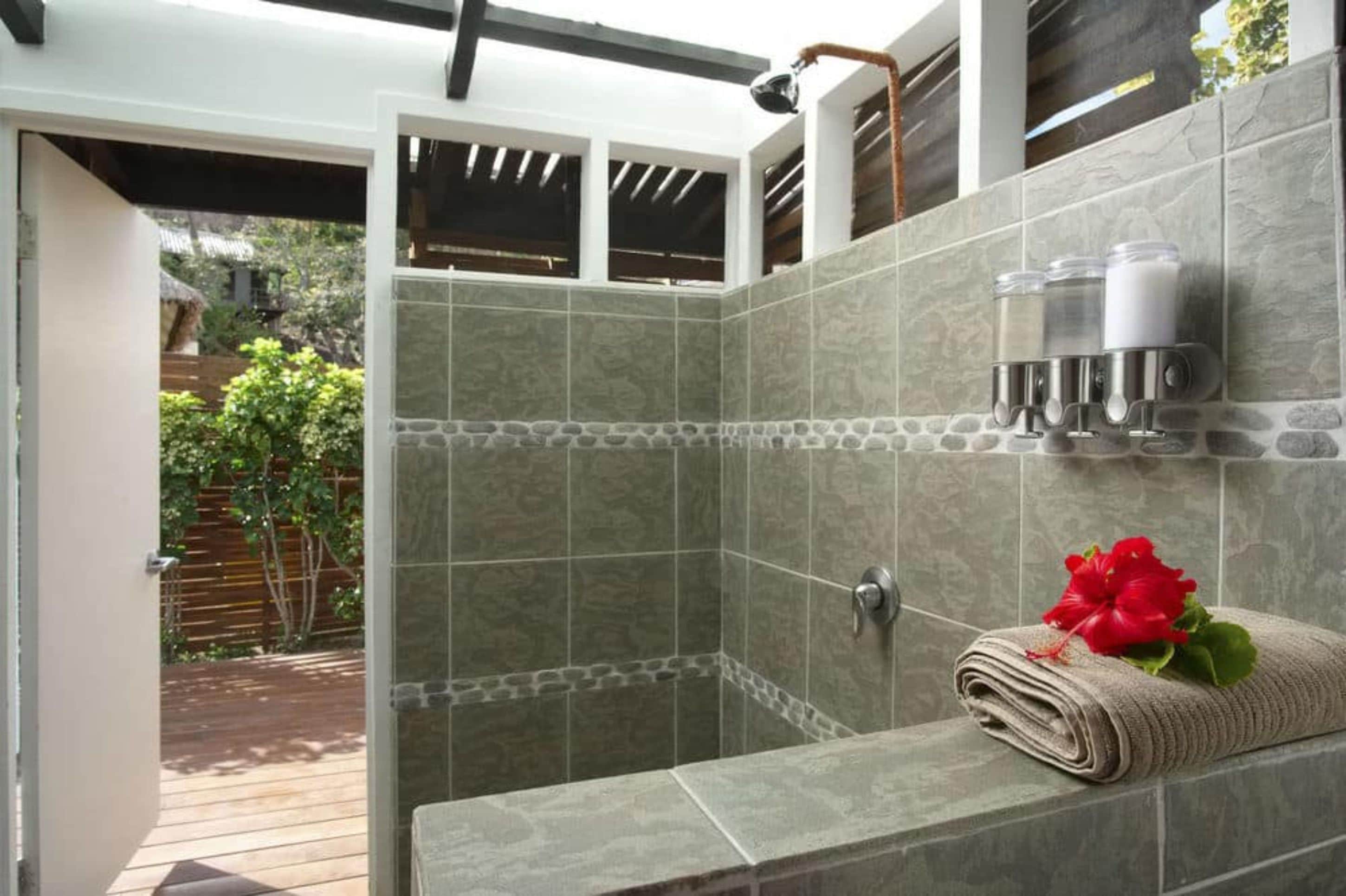 A shower area with stone tiles, a towel, and a red flower.