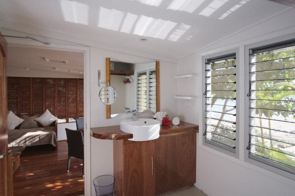 Un baño moderno con tocador de madera, un espejo grande y una ventana con persianas.