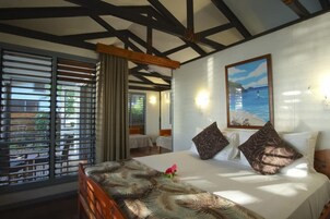 Habitación de hotel con una cama grande, un cuadro de una playa y vistas al exterior a través de la ventana.