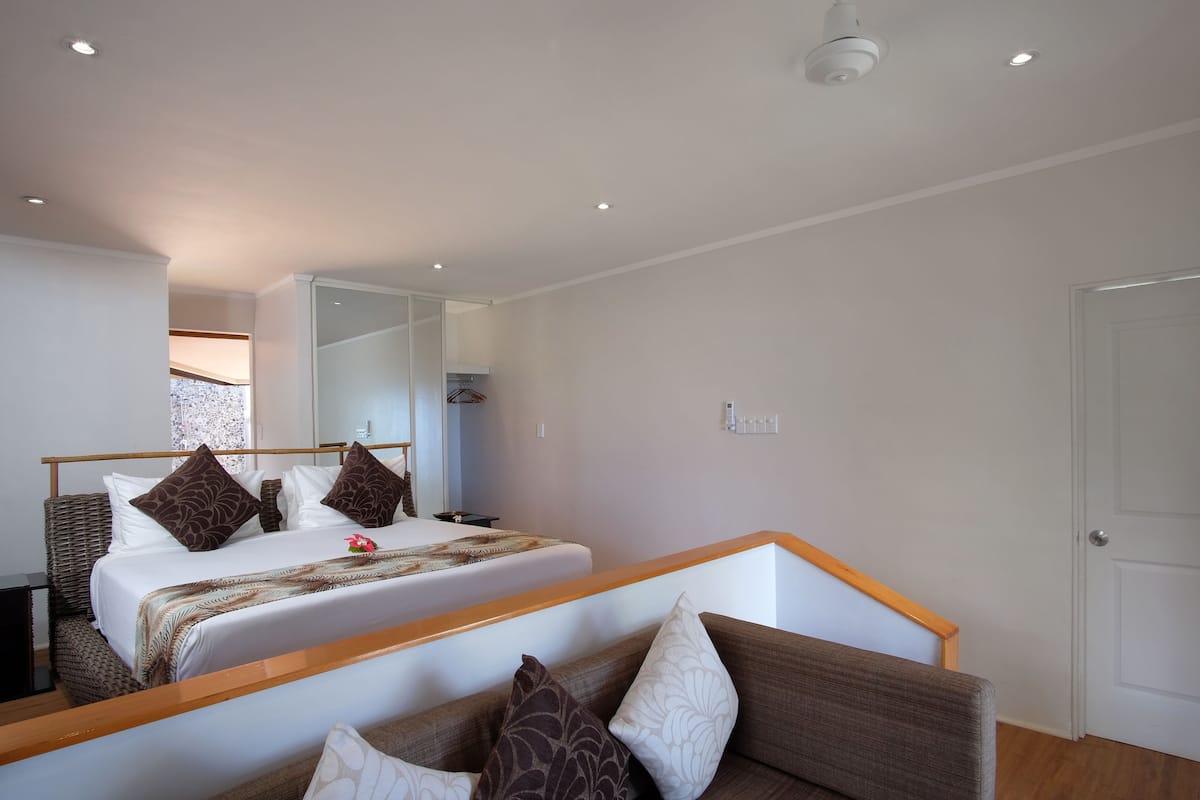 Ein modernes Hotelzimmer mit einem großen Bett, einer Couch und einem Spiegel, der den Raum wiederspiegelt.