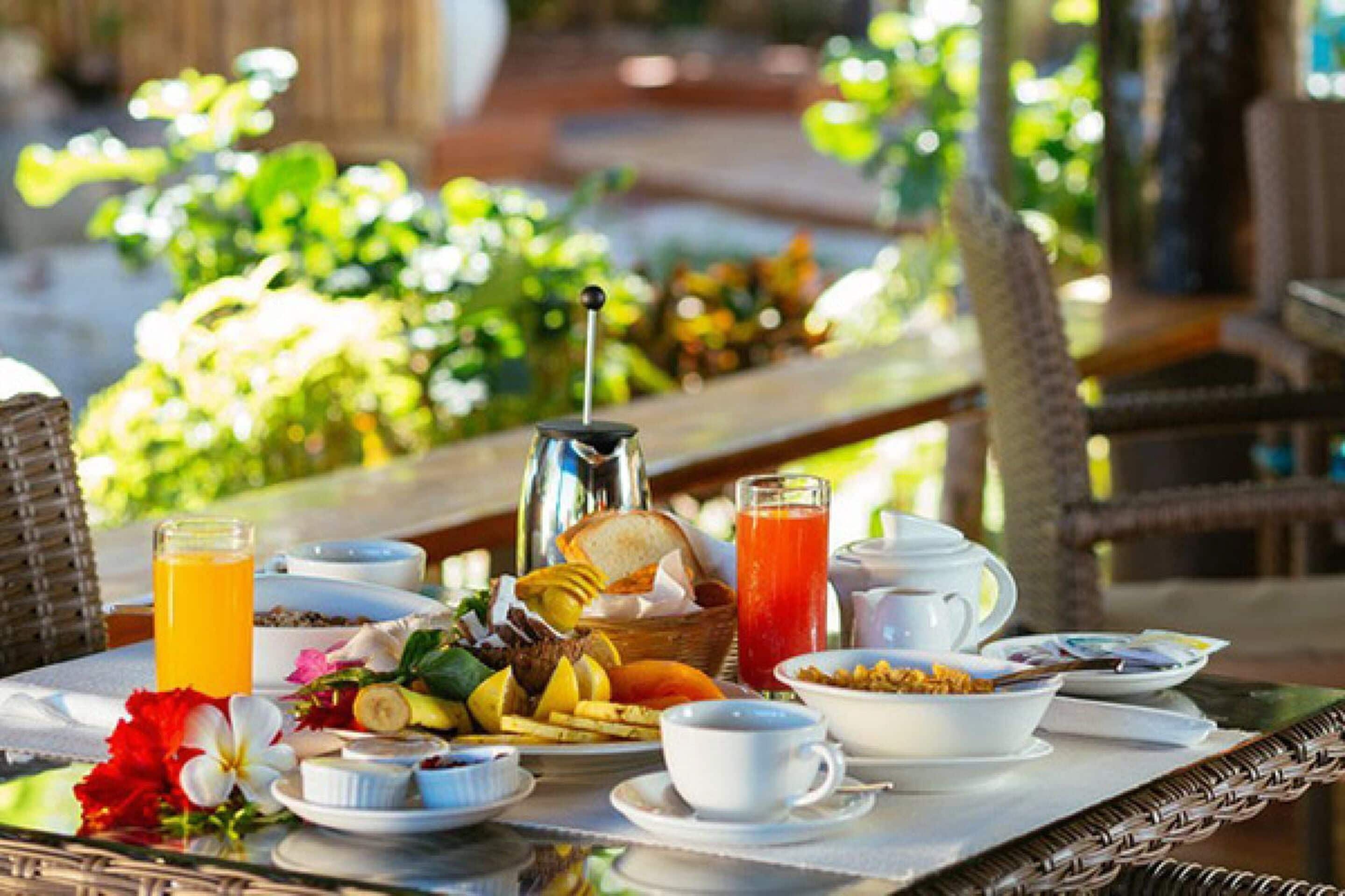 A breakfast table with various food items, a pitcher, and a glass of orange juice.