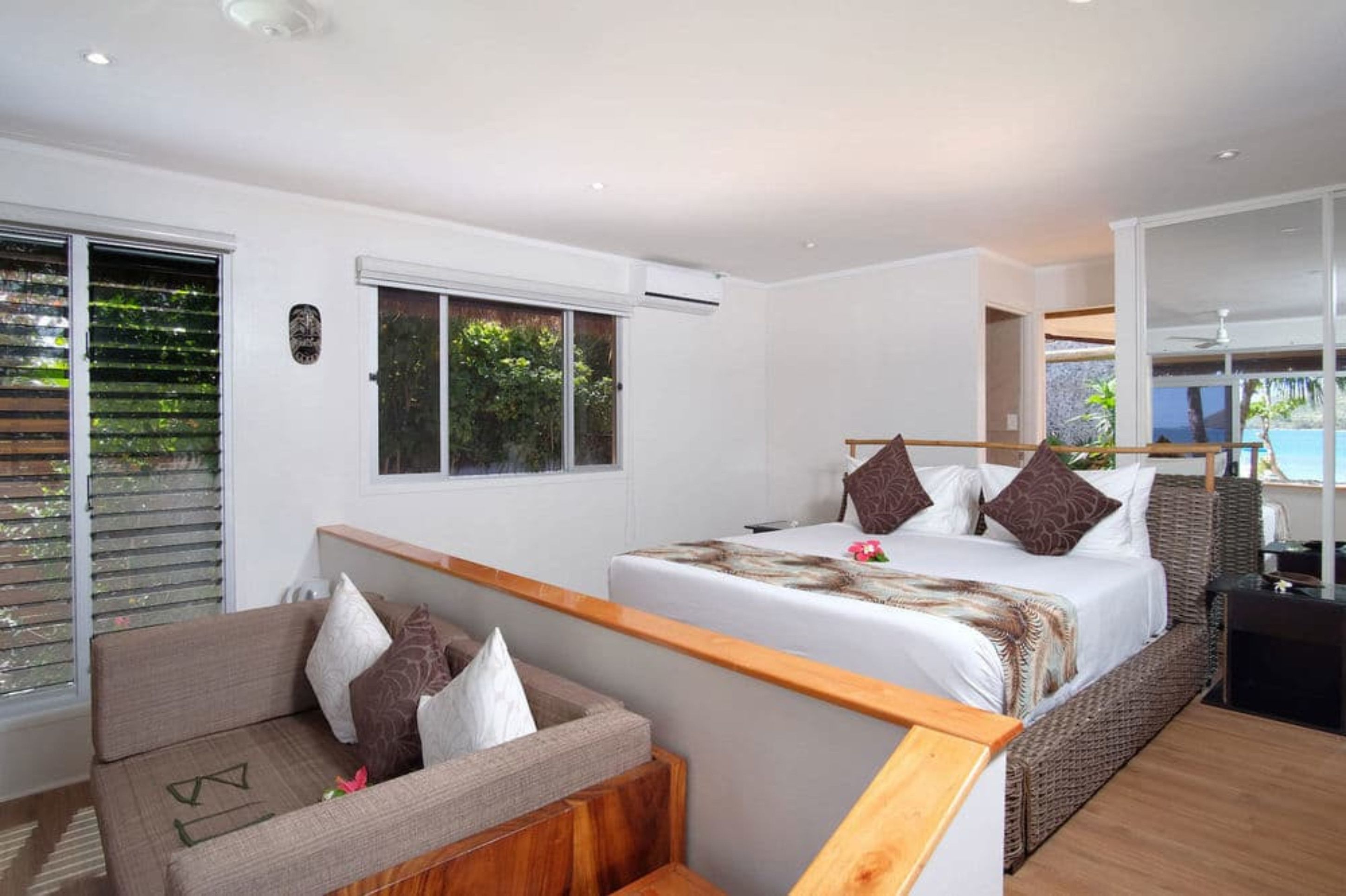 A bedroom with a bed, a sofa, and a view of the sea.