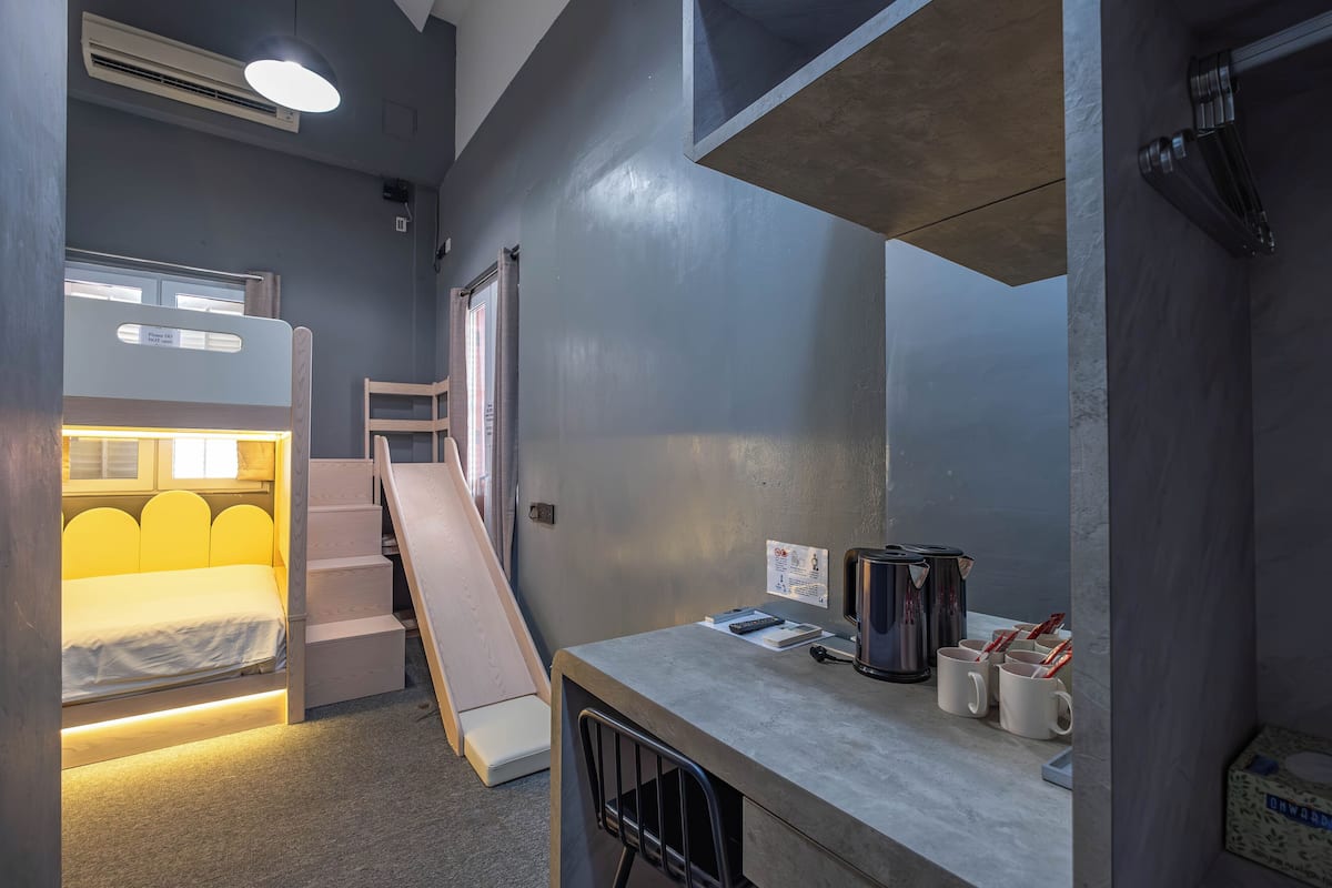 Habitación pequeña con literas, un escritorio y una zona de kitchenette.