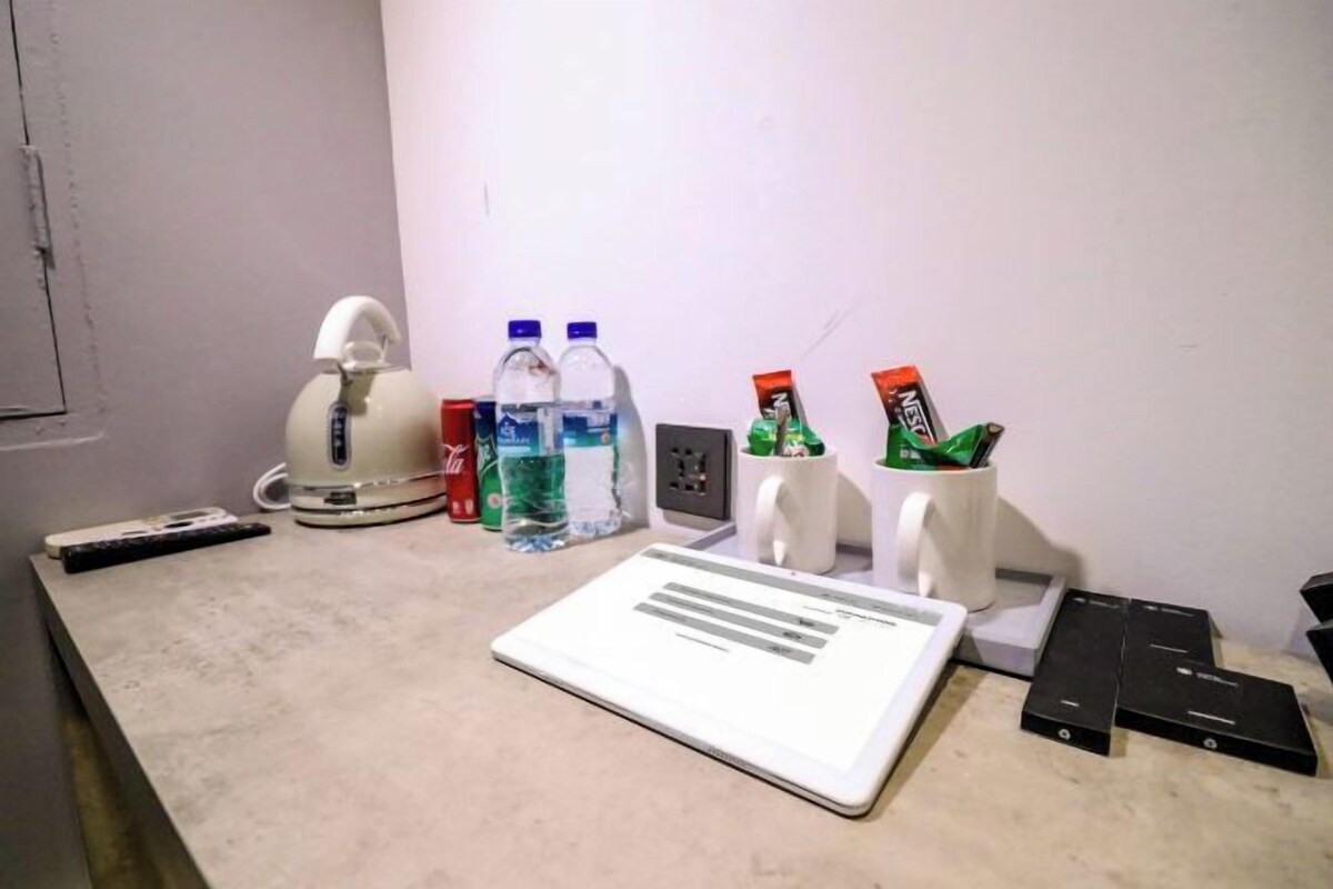 A desk with a laptop, a kettle, bottled water, and a mug.
