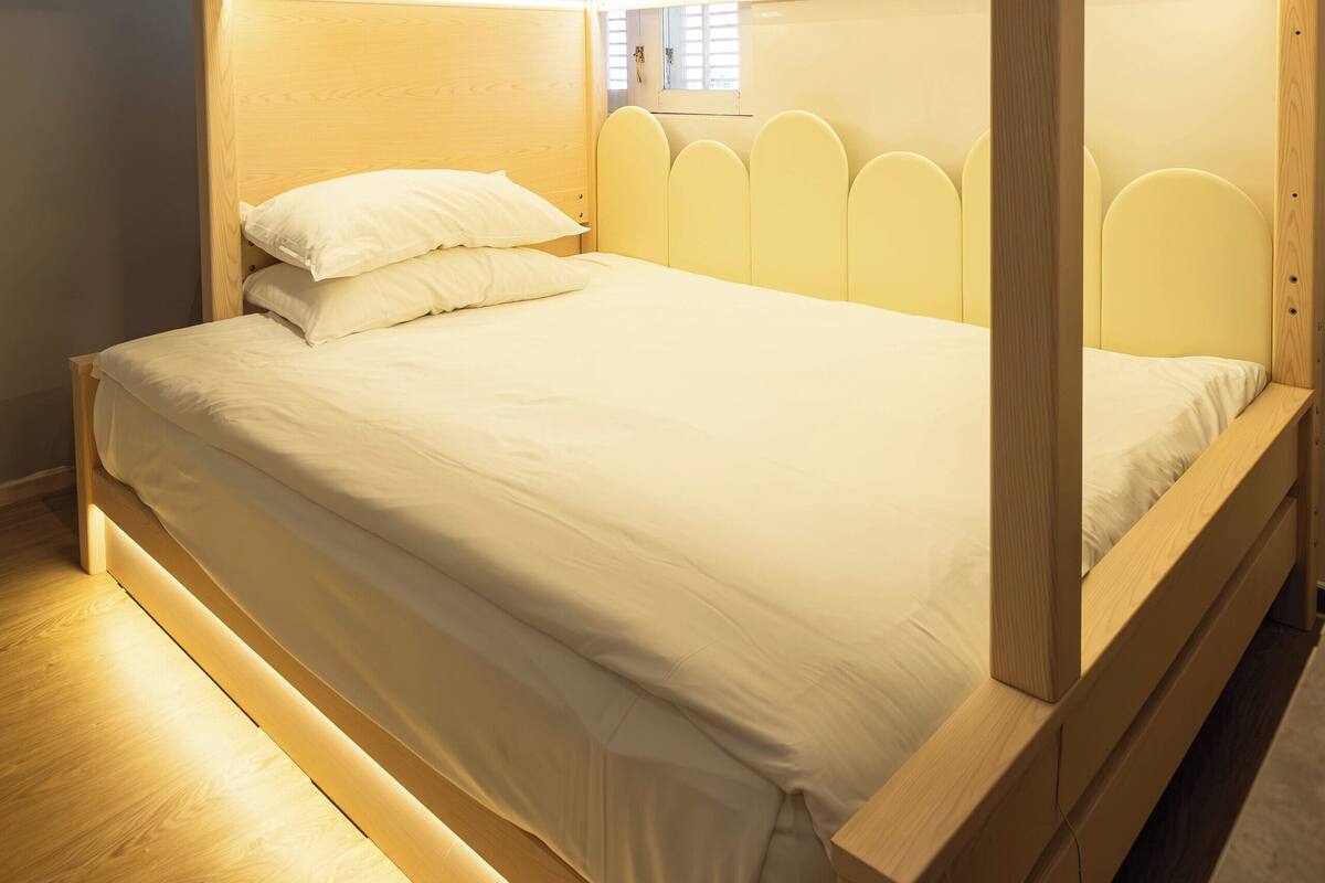 Una cama litera con estructura de madera y cabecero con diseños recortados.