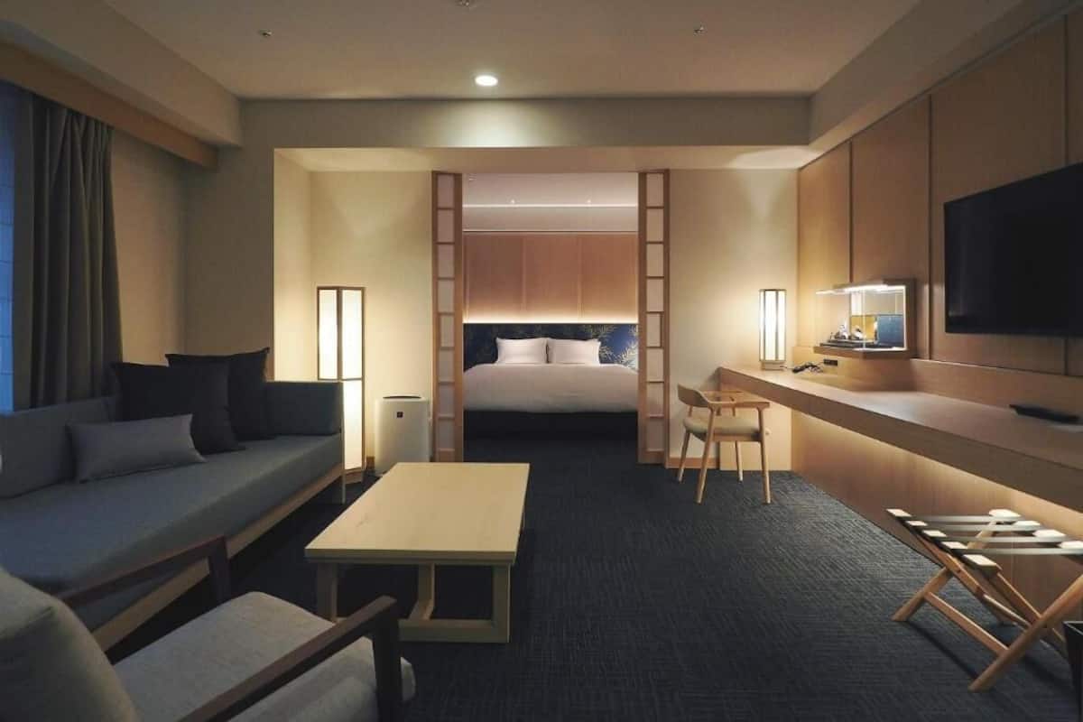 A hotel room with a bed, a desk, a sofa, and a TV.