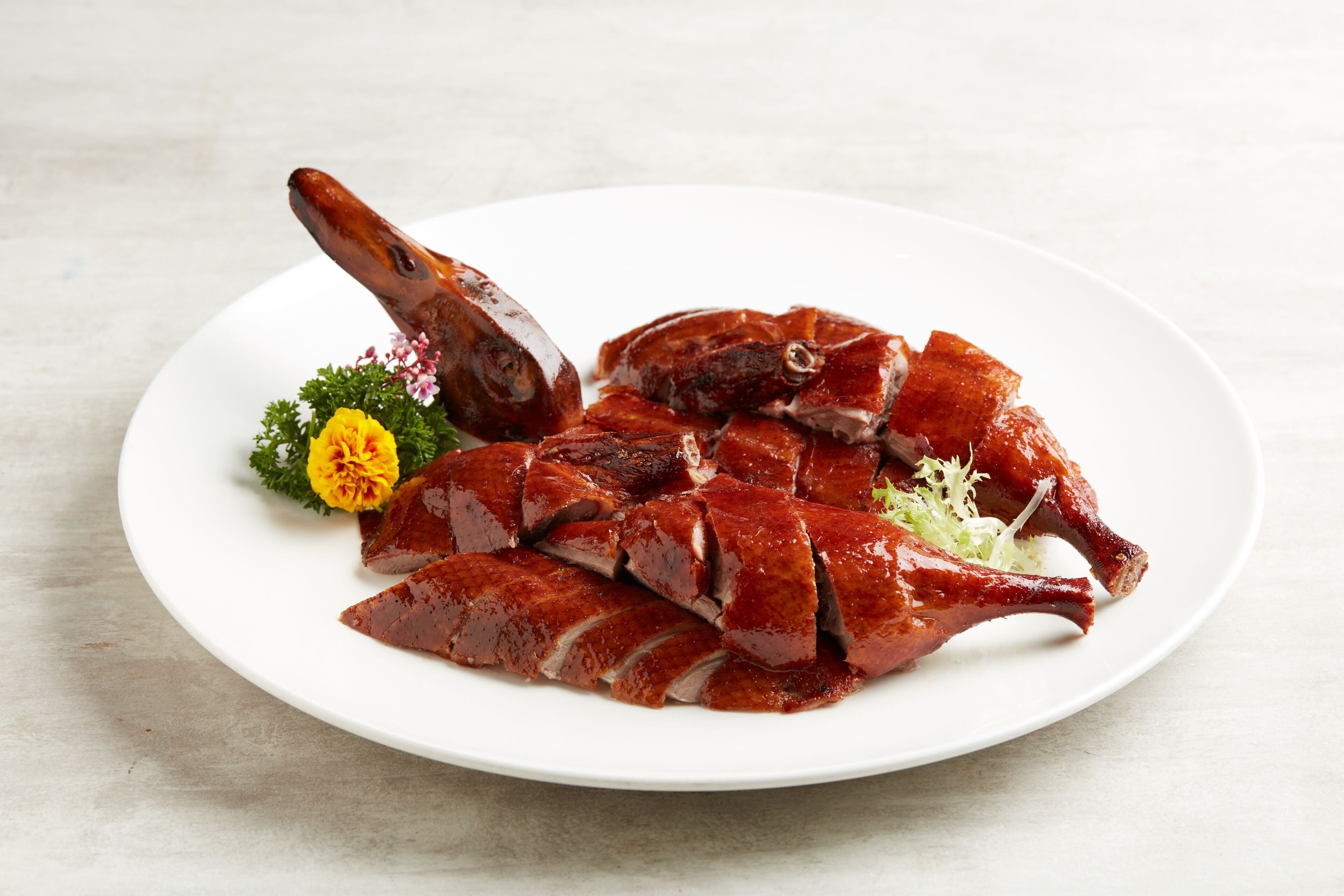 A plate of sliced duck with a decorative flower.