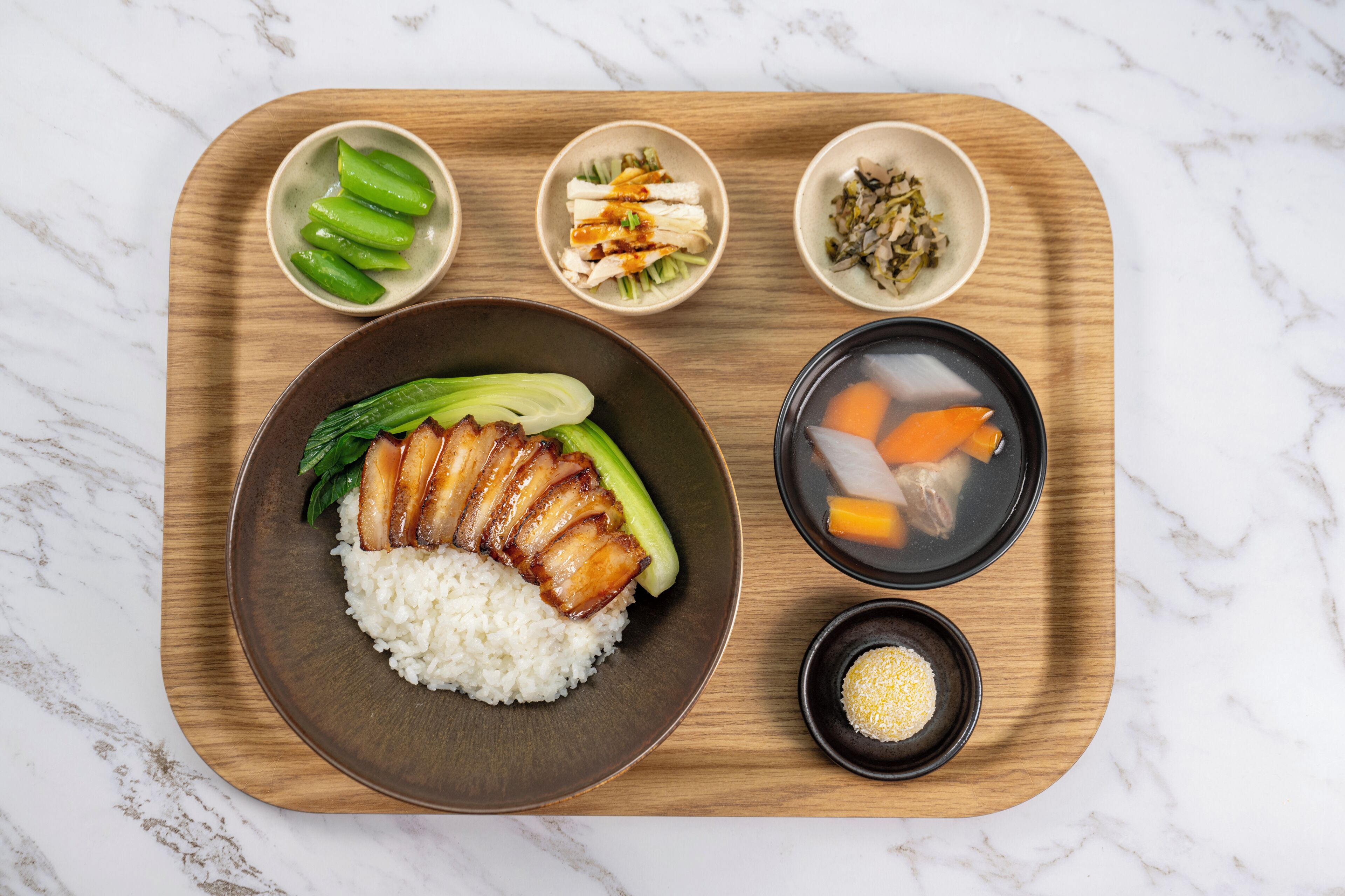 Una bandeja de madera con arroz, carne en rodajas y verduras, y tres recipientes pequeños con distintos alimentos.