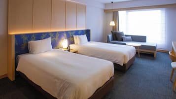 Ein Hotelzimmer mit zwei Betten, einem Schlafsofa, einem kleinen Tisch und einem Sessel.