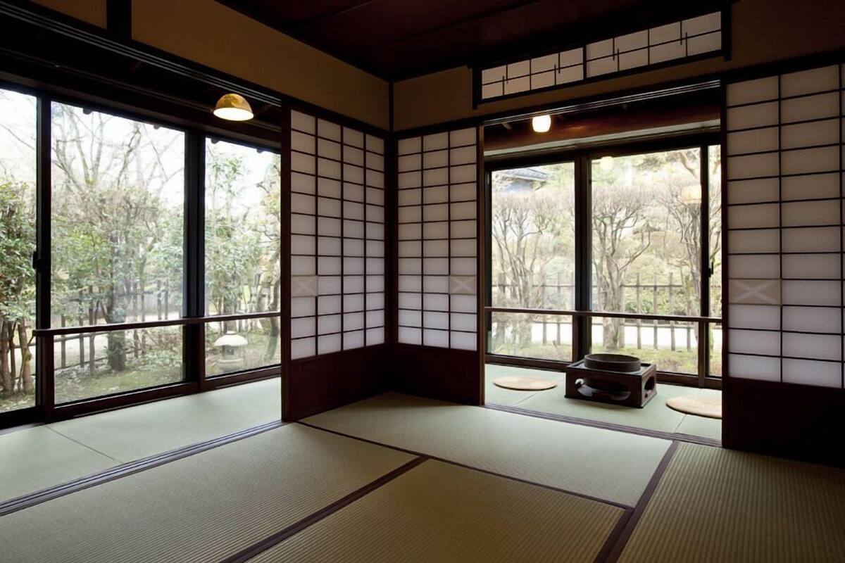 Une pièce de style japonais traditionnel, avec un sol recouvert de tatamis, des paravents shoji et une vue sur un jardin.