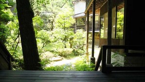 Une terrasse en bois offrant une vue sur un jardin et un bâtiment traditionnel.