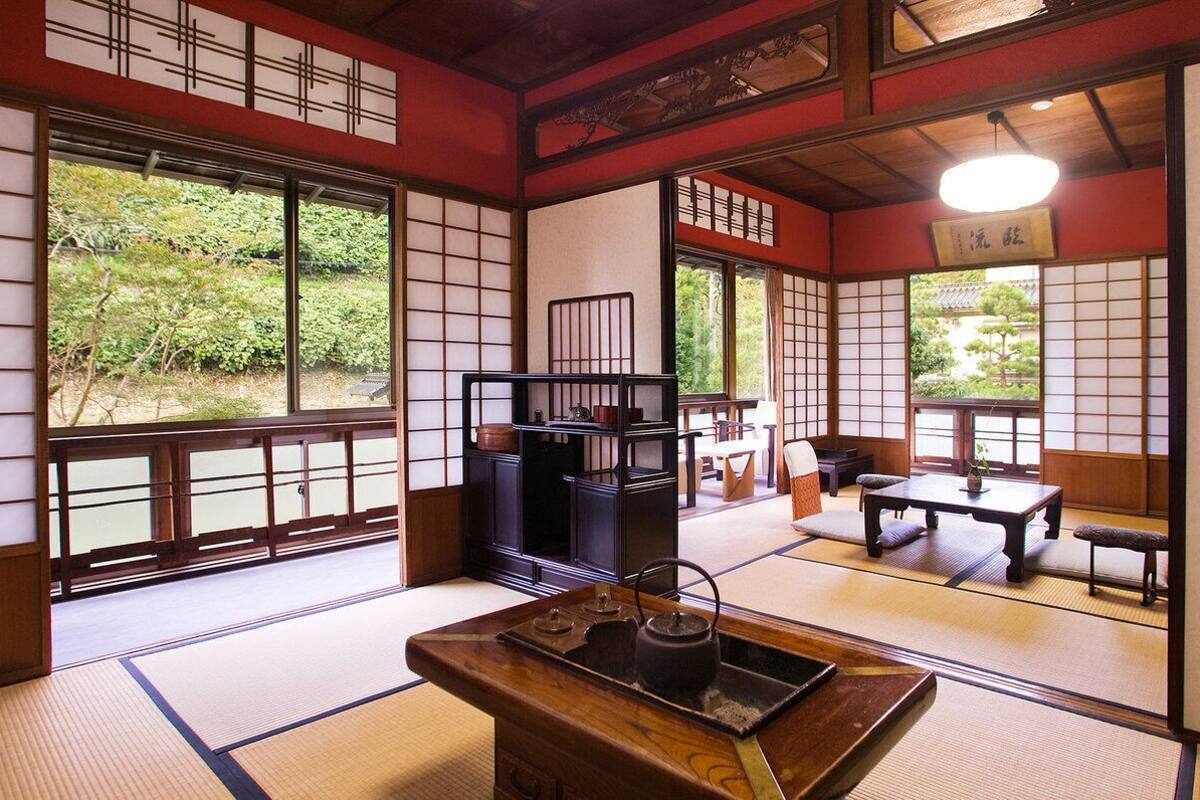 Une pièce de style japonais traditionnel, avec un sol recouvert de tatamis, des portes coulissantes et un service à thé posé sur une table en bois.