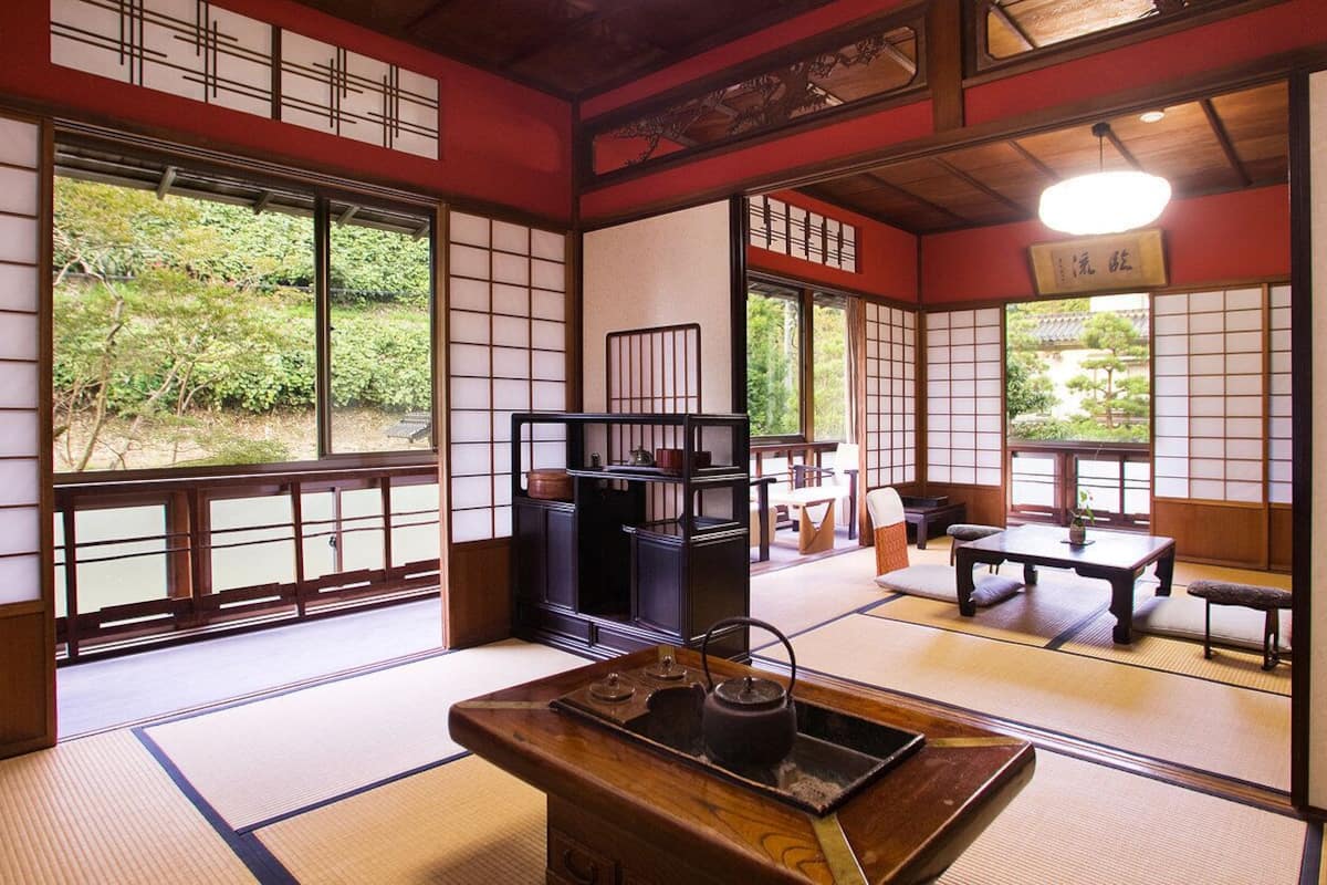 Una habitación japonesa tradicional con suelo de tatami, puertas correderas y un juego de té sobre una mesa de madera.