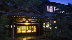 Un bâtiment japonais traditionnel, doté d’un toit recouvert de tuiles, d’une entrée abritée et d’une lanterne en pierre.