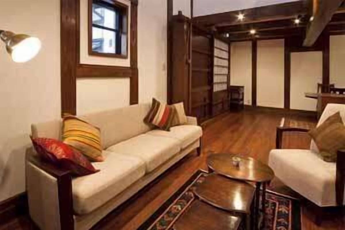 Un salon chaleureux avec un canapé, un fauteuil et une table basse, doté d’un parquet et agrémenté d’un tapis à motifs.