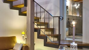 A modern interior with a wooden staircase, a sofa, a table with a glass, and a candle. - Kores Boutique Houses (Chania)