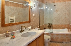 Un baño con lavamanos de mármol, inodoro y bañera.