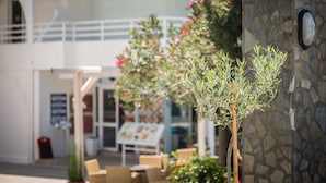 An outdoor seating area with tables and chairs, a stone wall, and potted plants. - Anika Studios (Rhodes)