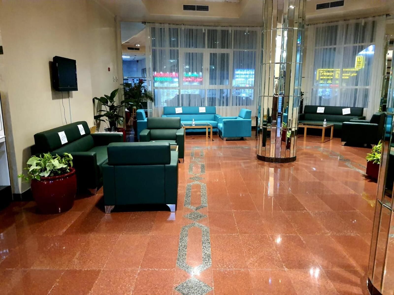 A lobby with green sofas, a coffee table, and potted plants.