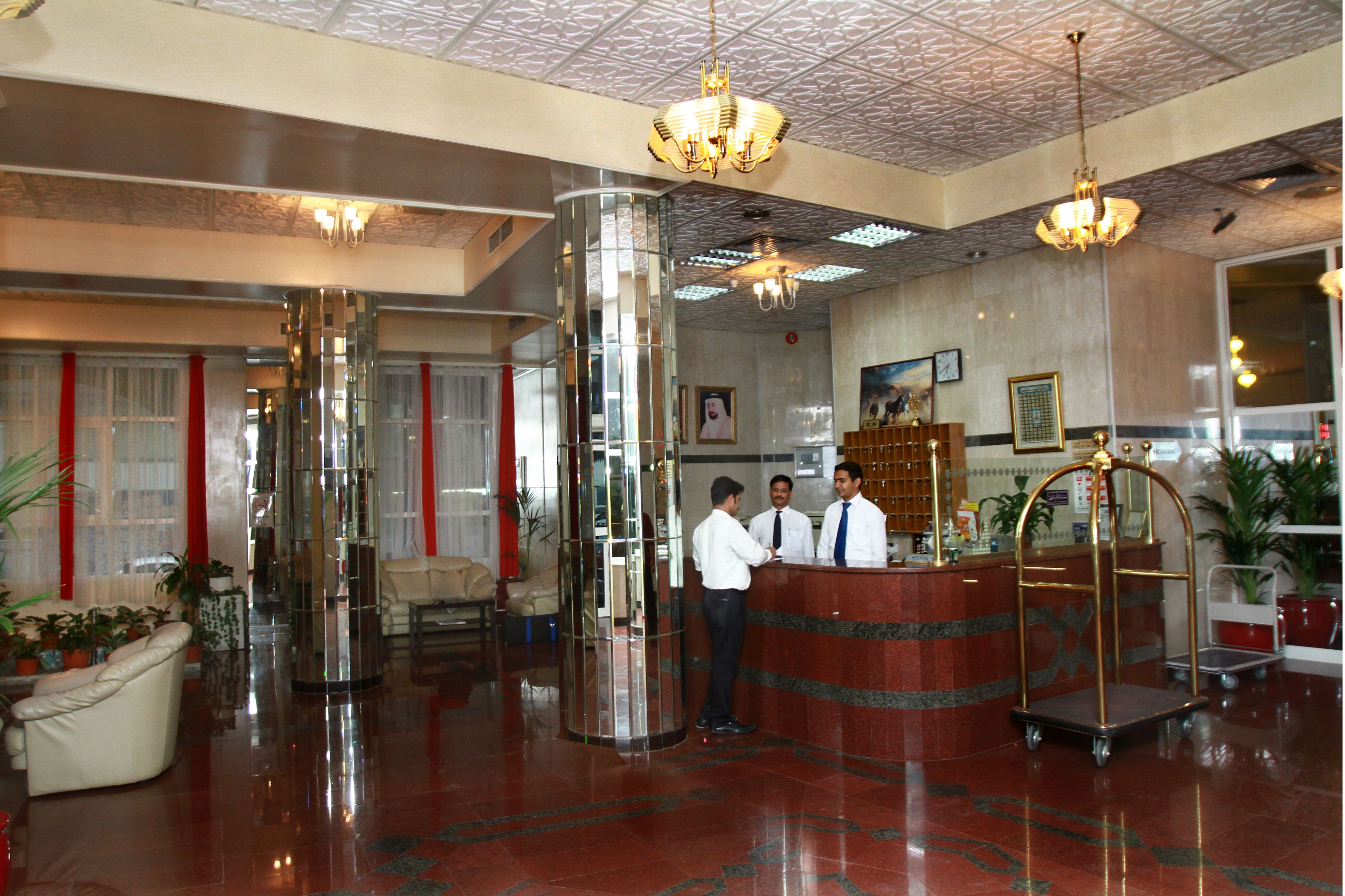 Un vestíbulo de hotel con una recepción, un espejo grande y un área de descanso con un sofá.