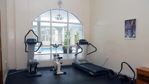 Un gimnasio con equipo de cardio, cinta de correr y máquina de remo.