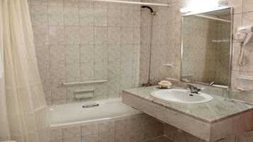 A bathroom with a bathtub, a sink, a mirror, and a hairdryer.