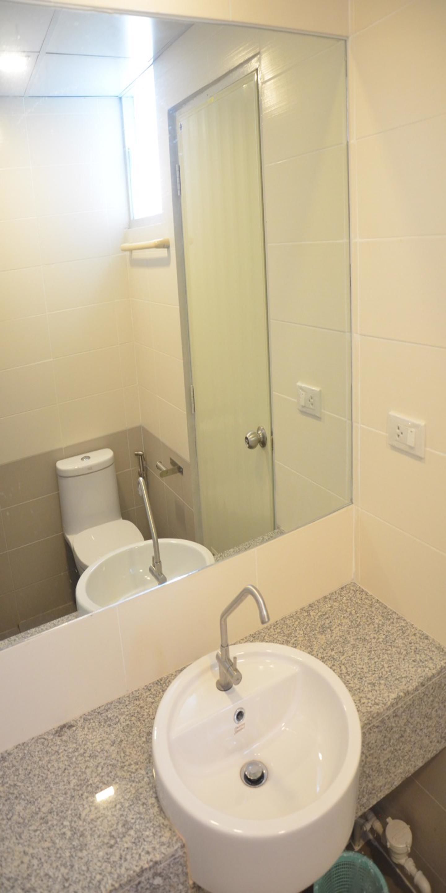 Un baño con lavamanos blanco, cabina de ducha de vidrio y un inodoro.