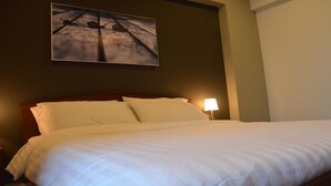 A neatly made bed with white linens in a hotel room. - LKP Apartment (Kanchanaburi)