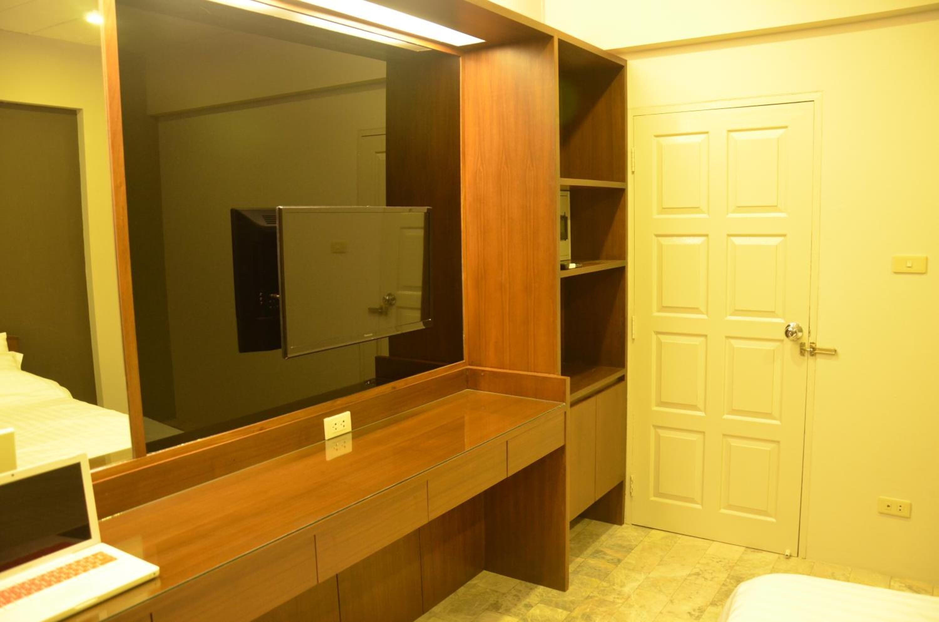 A bathroom with a wooden vanity, a mirror, a toilet, and a white door.