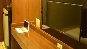 A hotel room with a wooden vanity, a laptop on the counter, and a large mirror. - LKP Apartment (Kanchanaburi)