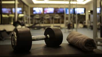 Un gimnasio con una mancuerna y una toalla sobre un banco.