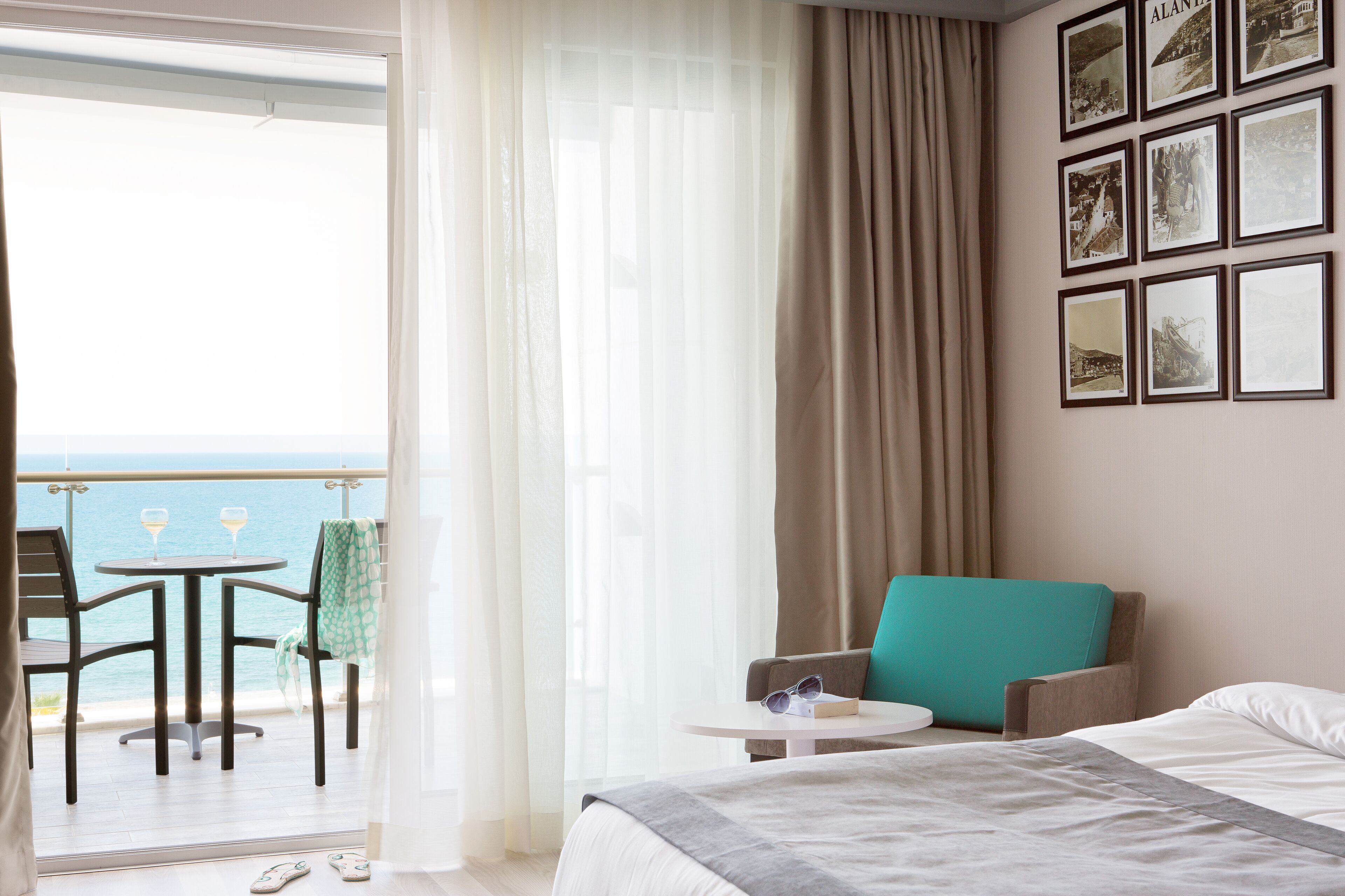 Habitación de hotel con cama, una silla, una mesita y vista al mar.