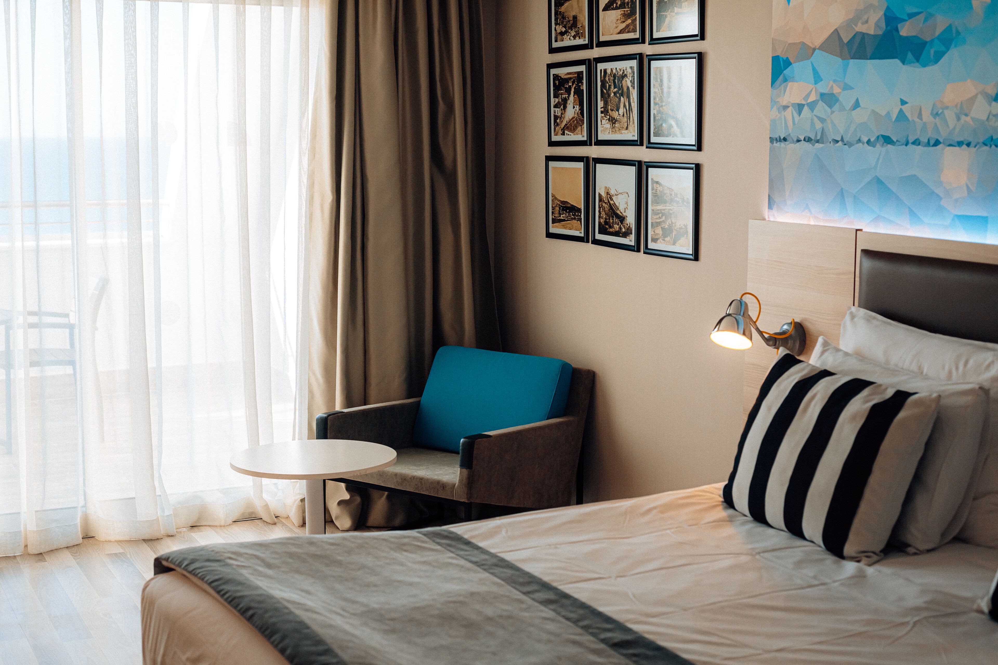 Une chambre d’hôtel avec un lit, une chaise, une petite table et un mur orné de tableaux.