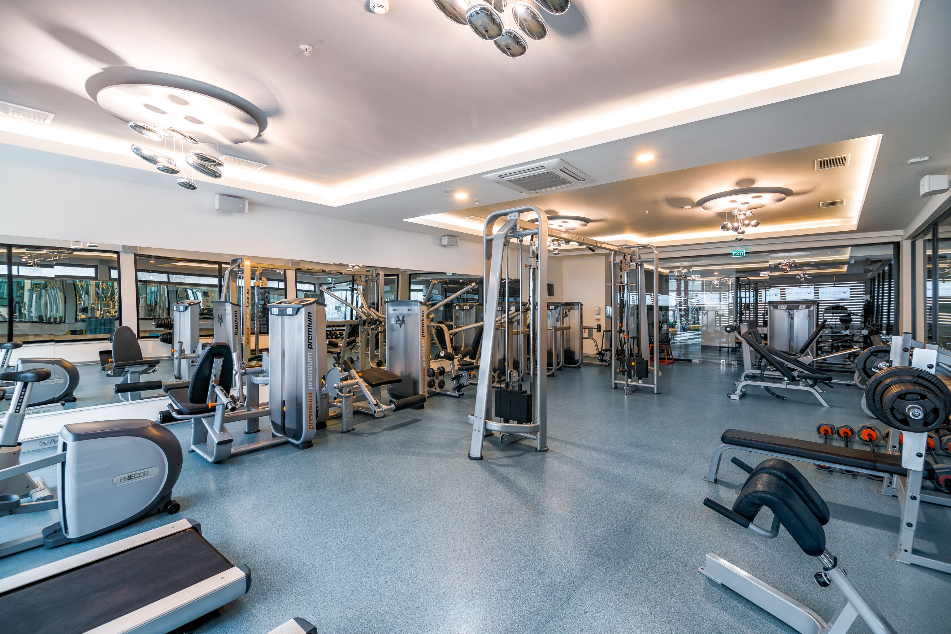 Ein modernes Fitnessstudio mit unterschiedlichen Trainingsgeräten, großen Fenstern und einer geräumigen Gestaltung.