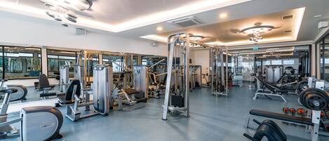 Ein modernes Fitnessstudio mit unterschiedlichen Trainingsgeräten, großen Fenstern und einer geräumigen Gestaltung.