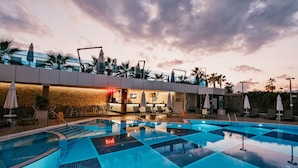 Une piscine dotée d’un bar, de chaises longues et de palmiers.