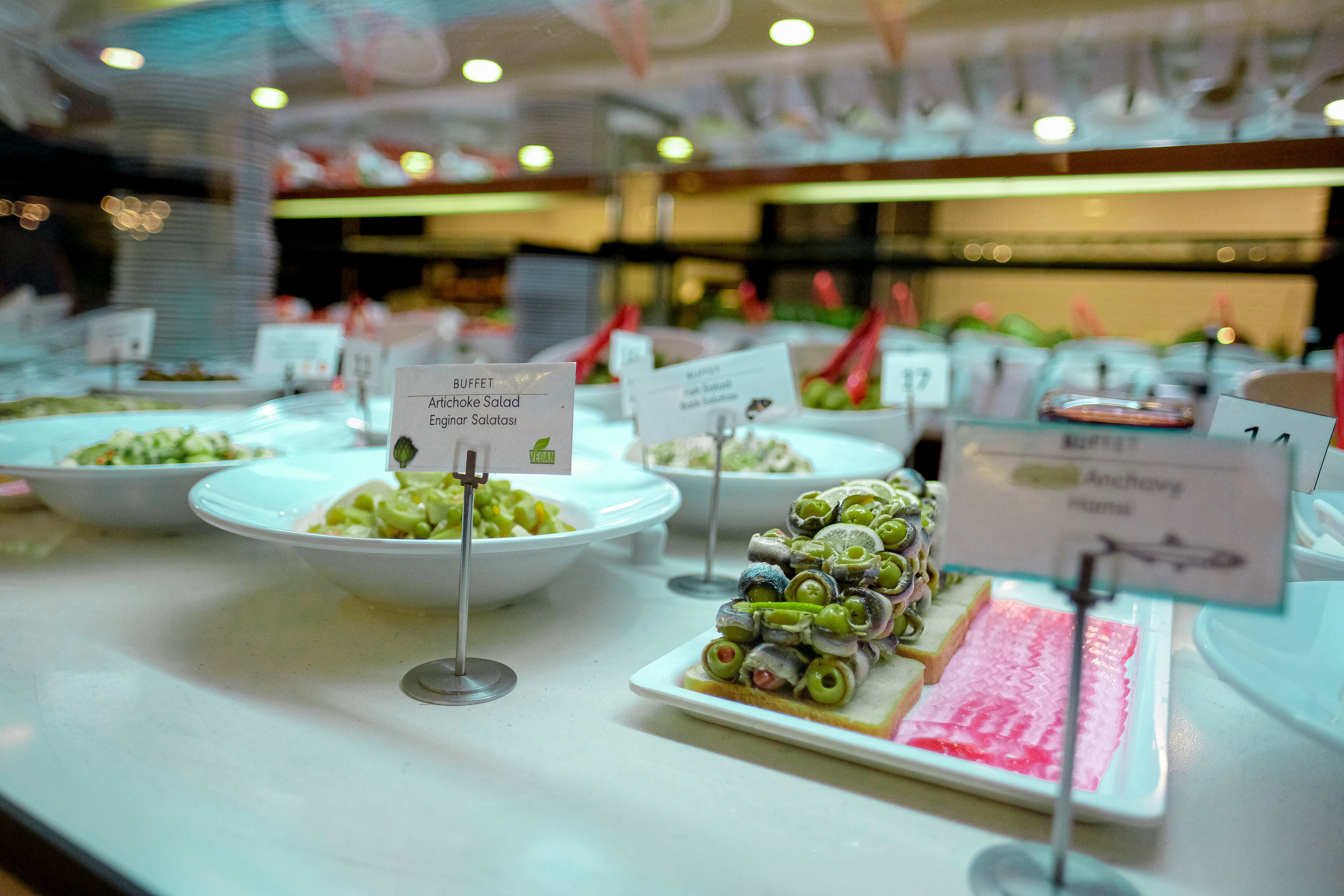 Un bufé con diversos platos, incluyendo una ensalada de boquerones y un plato con pescado y verduras.