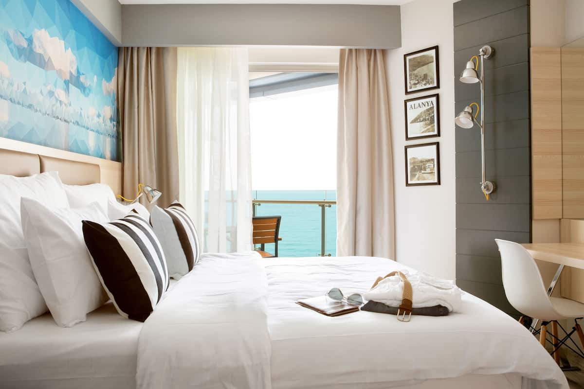 Une chambre d’hôtel avec un lit, un bureau et une vue sur la mer.