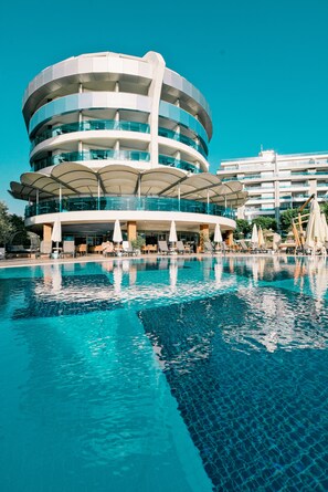 Una piscina al aire libre, sombrillas, tumbonas