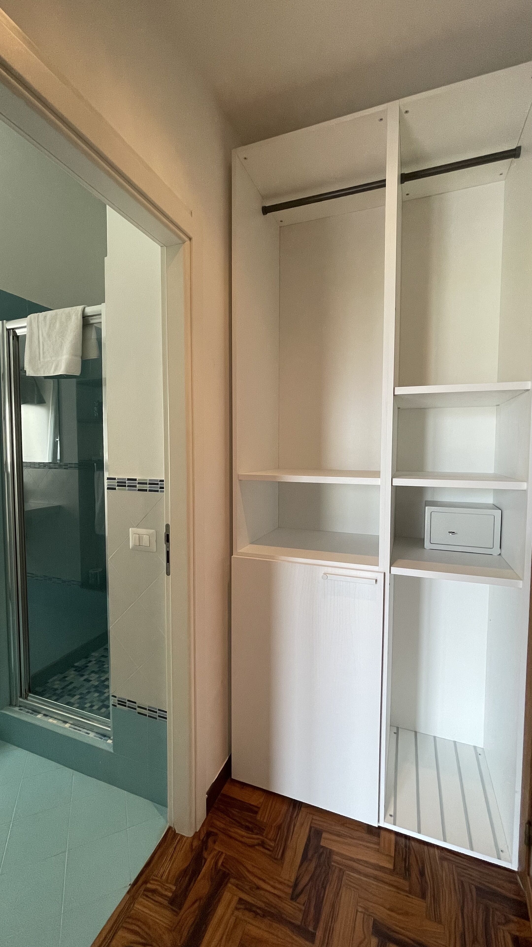 Un closet amplio con tres repisas y una pequeña caja fuerte.