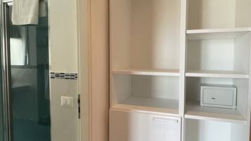 Un closet amplio con tres repisas y una pequeña caja fuerte.